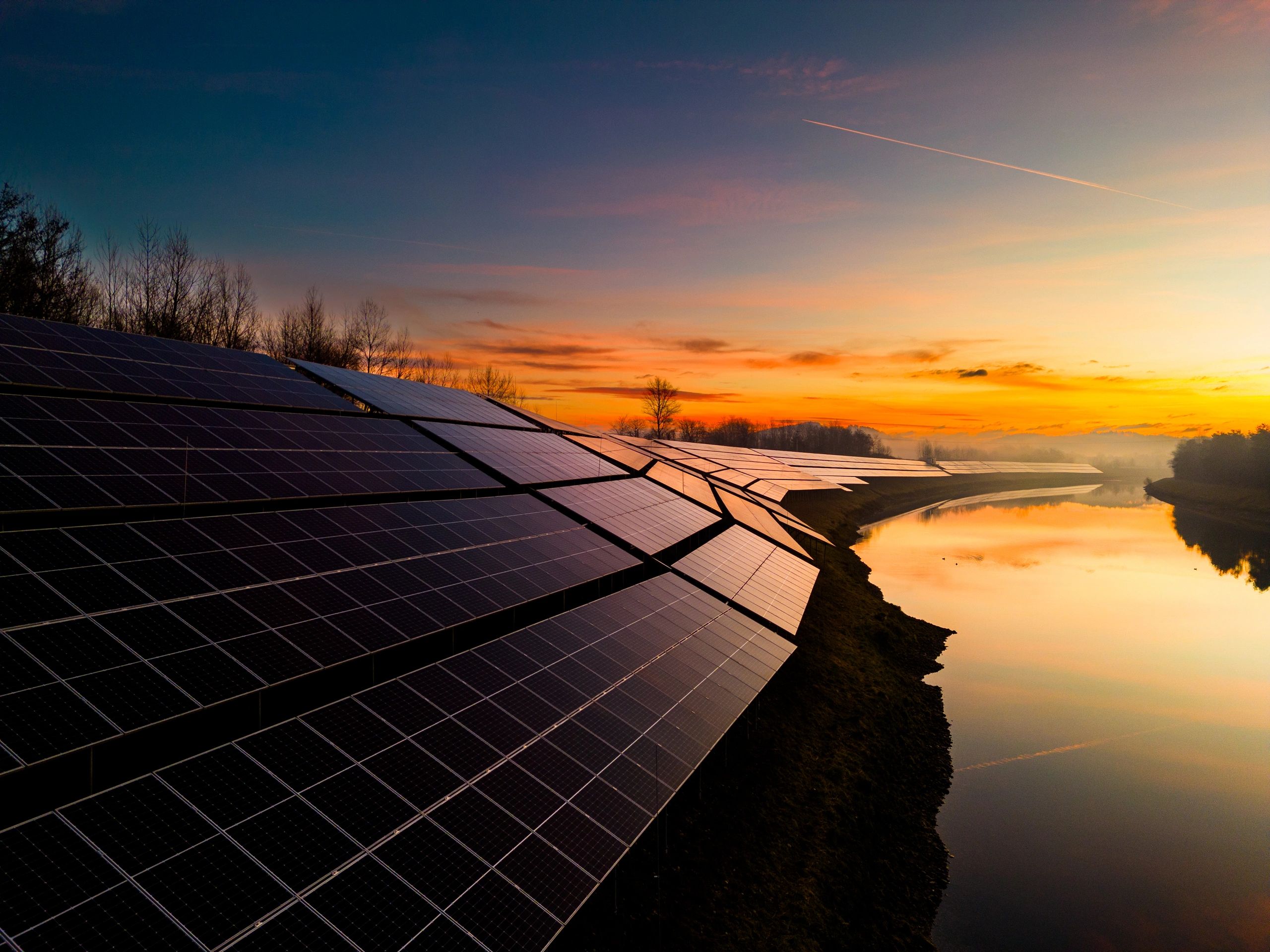 Solar power station near a river at sunset symbolizing clean energy and environmental stewardship
